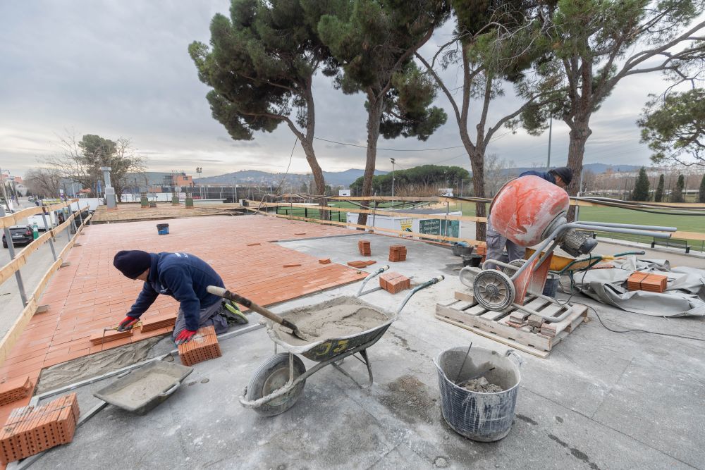 Dos obrers treballant en la taulada de l'edifici de vestuaris de la zona esportiva de La Bòbila