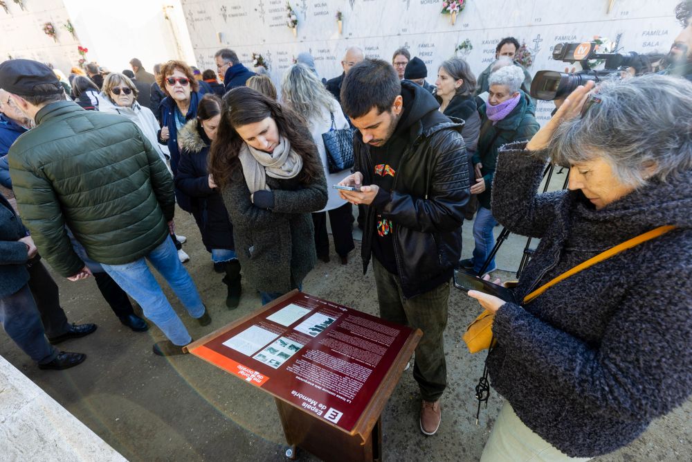 Persones llegint la senyalització de les fosses comunes